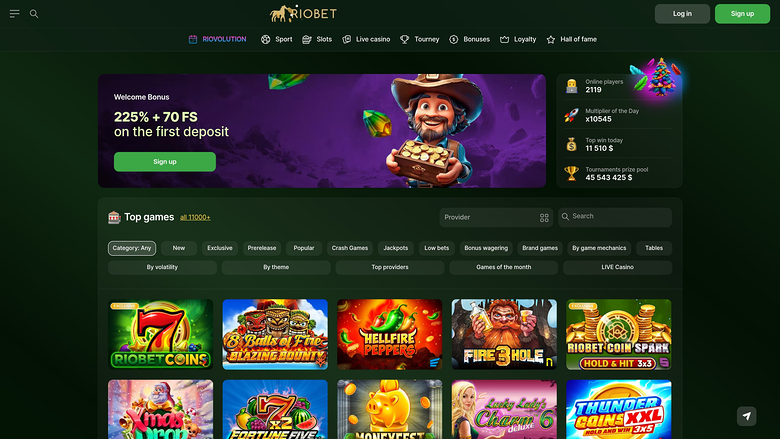 A dark-themed online casino lobby page for Riobet showing a welcome bonus banner, a top games filter bar and a grid of game tiles.